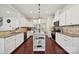 Well-lit kitchen features white cabinets, granite countertops, stainless steel appliances, and an island with storage at 9937 Travertine Trl, Davidson, NC 28036