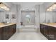 Bright bathroom featuring a soaking tub with decorative columns, dual sink vanities, and tile flooring at 11523 Warfield Ave, Huntersville, NC 28078