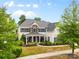 Two-story home featuring stone accents, a covered porch with seating, mature trees, and a well-manicured lawn at 11523 Warfield Ave, Huntersville, NC 28078