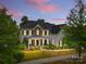 Beautiful two-story home featuring stone accents, covered porch, manicured landscaping, and walkway lighting at twilight at 11523 Warfield Ave, Huntersville, NC 28078