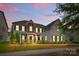 Charming two-story home with stone accents, covered porch, manicured landscaping and illuminated by accent lights at twilight at 11523 Warfield Ave, Huntersville, NC 28078