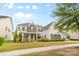 Inviting two-story home with stone detailing, a covered porch, mature trees, and a well-maintained front lawn at 11523 Warfield Ave, Huntersville, NC 28078