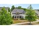 Stately two-story home featuring stone accents, a covered porch with seating, and mature landscaping at 11523 Warfield Ave, Huntersville, NC 28078