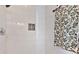 Close-up of a shower with white and beige tiling and a small inset of mosaic tiling at 127 Charlotte St, Mooresville, NC 28115