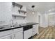 A close up of a kitchen with white cabinets, black countertops, subway tile backsplash, and stainless steel double sink at 211 Heritage Blvd # 301, Fort Mill, SC 29715