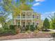Charming yellow two-story home with white pillars, balcony, landscaped yard and inviting front porch at 2009 Waterbury Ln, Waxhaw, NC 28173