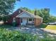 Charming red brick home featuring a cozy front porch and well-maintained yard and driveway at 301 Louise St, Lancaster, SC 29720