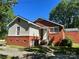 A red brick home featuring a cozy front porch, and a green grass yard at 301 Louise St, Lancaster, SC 29720