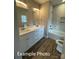 Bathroom with double sinks, white cabinets, marble-look tile, and a bathtub at 318 Stanback St, Mount Gilead, NC 27306