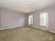 Empty bedroom with light purple walls, green carpet, two windows and white trim at 557 S Portman Ln, Fort Mill, SC 29708
