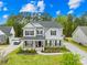 Inviting two-story home featuring stone accents, black shutters, covered porch, and lush landscaping at 121 Pine Eagle Dr, Rock Hill, SC 29732