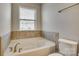 Bathroom featuring a soaking tub with tile surround and a window with blinds at 1213 Bhaltair Ln, Fort Mill, SC 29708