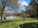 Lush backyard with grassy lawn leading to a sandy beach and private dock overlooking a tranquil lake at 126 Balmoral Dr, Mooresville, NC 28117