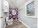 Bathroom featuring gray walls, laminate flooring, a toilet, cabinet and a floral shower curtain at 128 Allenton St, Norwood, NC 28128