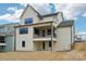 Back exterior of a three-story home with black trim, a patio, and a second story balcony at 163 Windy Dell Dr, Tega Cay, SC 29708