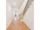 Bright hallway with hardwood floors leading to an outdoor view and a staircase with black metal spindles at 163 Windy Dell Dr, Tega Cay, SC 29708