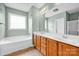 Bright bathroom with a dual sink, wooden cabinets, and a large mirror above at 16606 Spruell St, Huntersville, NC 28078