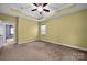 Bright, carpeted bedroom has tray ceiling and large window with natural light at 16606 Spruell St, Huntersville, NC 28078