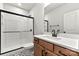 Modern bathroom featuring a glass shower door, patterned tile floor, and wood vanity with black hardware at 3050 Tramore Dr, Harrisburg, NC 28075