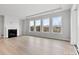 Bright, neutral living room featuring a fireplace, hardwood floors, and large windows offering natural light and treetop views at 3050 Tramore Dr, Harrisburg, NC 28075