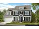 Two-story home featuring gray siding, black shutters, stone accents, a covered porch, and an attached garage at 3057 Tramore Dr, Harrisburg, NC 28075