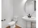 Modern powder room features a floating sink with matte black faucet, a round mirror, and a toilet at 3057 Tramore Dr, Harrisburg, NC 28075