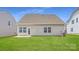 A backyard features a well-maintained lawn and a neutral-colored exterior with windows and a door leading to a patio at 4171 Skyboat Cir, Fort Mill, SC 29715