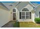 A welcoming front entrance boasts a beautiful wood door, arched windows, and manicured landscaping at 6821 Parkers Crossing Dr, Charlotte, NC 28215