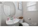 Cozy powder room features a pedestal sink, round mirror, and a window providing natural light at 10241 Barrands Ln, Charlotte, NC 28278