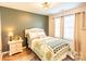 Bright bedroom featuring a decorative quilt, bedside table, and natural light from the windows at 118 Heathrow Ln, Statesville, NC 28677