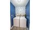 Functional laundry area with modern washer and dryer, stylish wallpaper, and storage shelf at 118 Heathrow Ln, Statesville, NC 28677