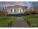 Charming home with inviting porch, black shutters, and well-manicured lawn at dusk at 1411 Congress St, Gastonia, NC 28054