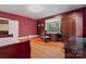 Red-walled bedroom boasts hardwood floors, a large window, a desk, and a comfortable area at 1500 Griffith Rd, Monroe, NC 28112