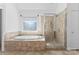 Well-lit bathroom with a soaking tub, glass shower, and neutral tiling at 15009 Lisha Ln, Charlotte, NC 28277