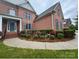 Charming brick home featuring a landscaped front yard with colorful flower beds and a covered front porch at 15009 Lisha Ln, Charlotte, NC 28277