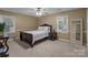 Comfortable bedroom featuring neutral carpeting, a queen bed, and a decorative mirror at 16421 Breckshire Dr, Huntersville, NC 28078
