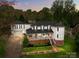 Charming two-story home with a brick foundation, white siding, covered front porch, and a separate two-car garage at 16421 Breckshire Dr, Huntersville, NC 28078