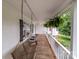 Inviting covered front porch featuring a wooden swing, white railings, and hanging plants, creating a welcoming outdoor space at 16421 Breckshire Dr, Huntersville, NC 28078