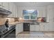 Well-lit kitchen with stainless steel sink, oven, and white cabinets at 16421 Breckshire Dr, Huntersville, NC 28078