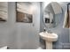 Stylish powder room featuring a pedestal sink, round mirror, and tasteful wall decor at 1986 Thoreau Way, York, SC 29745