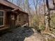 Rear exterior view of a rustic home with a stone patio and wooded surroundings at 2018 Fox Creek Trl, Lincolnton, NC 28092