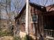 Side exterior view of a rustic home with a chimney and wood-paneled facade at 2018 Fox Creek Trl, Lincolnton, NC 28092