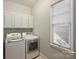 Bright laundry room featuring a modern washer, dryer, white cabinets, and natural light at 2021 Nolen Park Ln, Charlotte, NC 28209