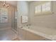 Bright bathroom featuring soaking tub, separate shower, and shutters for natural light at 2021 Nolen Park Ln, Charlotte, NC 28209