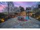 Enjoy twilight in this backyard featuring a pool, fire pit, and beautiful landscaping at 2132 Rolston Dr, Charlotte, NC 28207