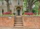 Charming home entrance featuring a brick wall, lush landscaping, and an elegant arched doorway with columns at 2132 Rolston Dr, Charlotte, NC 28207