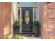 Elegant front door with decorative glass, black planters and brick surround at 221 Colony Dr, Mooresville, NC 28115