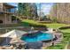 Beautiful backyard pool with a waterfall feature, built-in grill, and lounge chairs at 221 Colony Dr, Mooresville, NC 28115