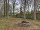View of brick fire pit in back yard with trees and wooden fence at 4427 Gaynelle Dr, Charlotte, NC 28215