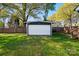Detached white garage situated on green grass, surrounded by mature trees and a wooden fence at 48 Mandalay Sw Pl, Concord, NC 28027